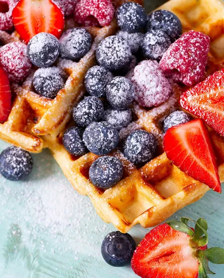 Strawberries, blueberries, sugar on top of waffles