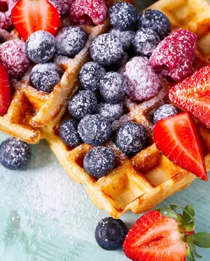 Strawberries, blueberries, sugar on top of waffles
