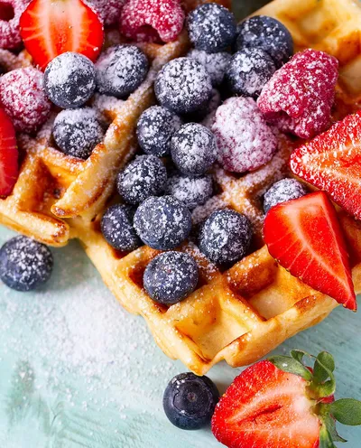 Strawberries, blueberries, sugar on top of waffles