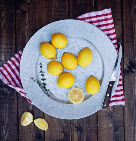 Six lemons, knife, and towel on table