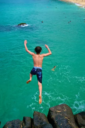 Boy jumping into ocean