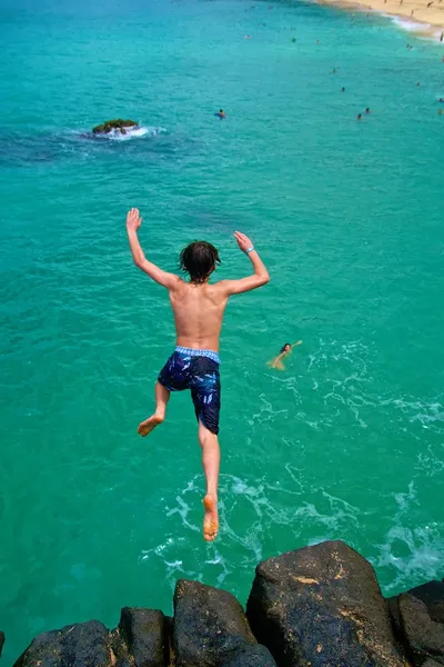Boy jumping into ocean
