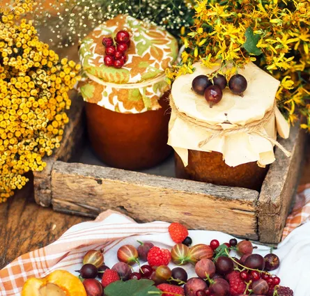 Delicious jars of jam in crate, surrounded by fresh fruit and fall foliage