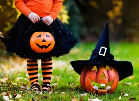 Halloween, witch hat, witch costume, pumpkin carving, halloween decoration, child standing next to jack o lantern, happy halloween