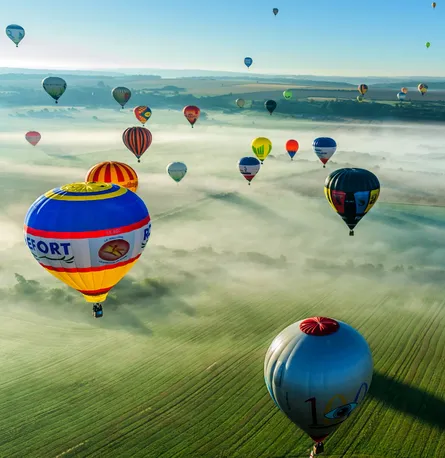 Multiple colorful hot air balloons, daytime flight
