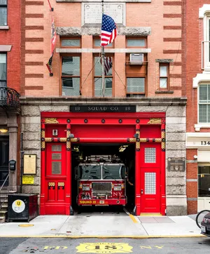 Red fire truck parked in front of red fire station
