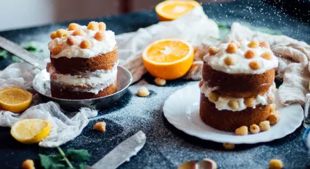 Double layered cake, frosted, topped with sliced oranges and almonds