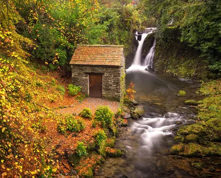 Old cabin next to waterfall