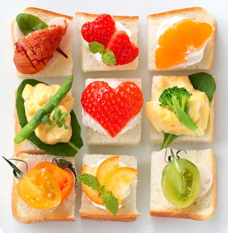 Six sandwiches with sliced fruit on top