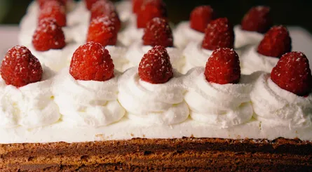 Rows of strawberries on top of cream cheese frosted cake