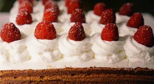 Rows of strawberries on top of cream cheese frosted cake