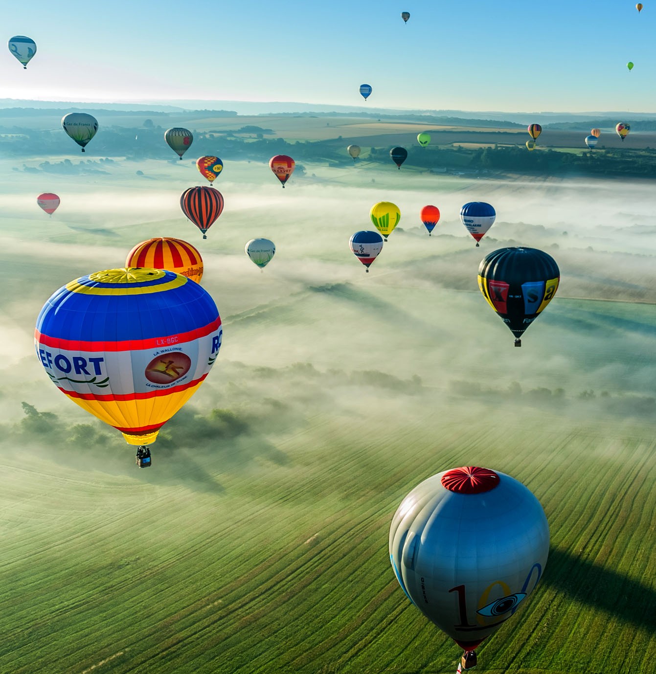 Multiple colorful hot air balloons, daytime flight